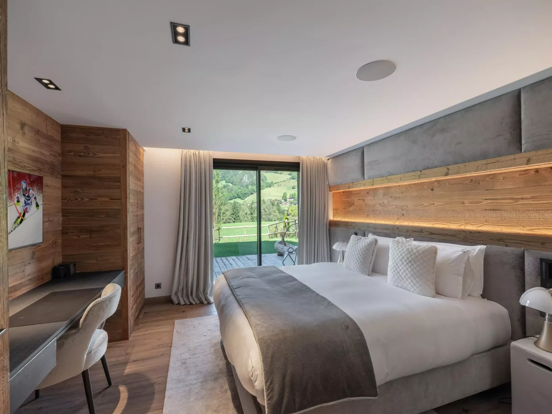 Un dormitorio con una cama grande, paredes revestidas de madera y una puerta de vidrio con vista a la vegetación.