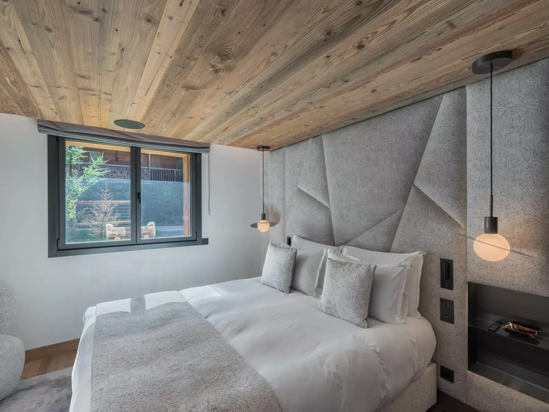 Un dormitorio con una cama bajo un techo revestido de madera y paneles geométricos en la pared.