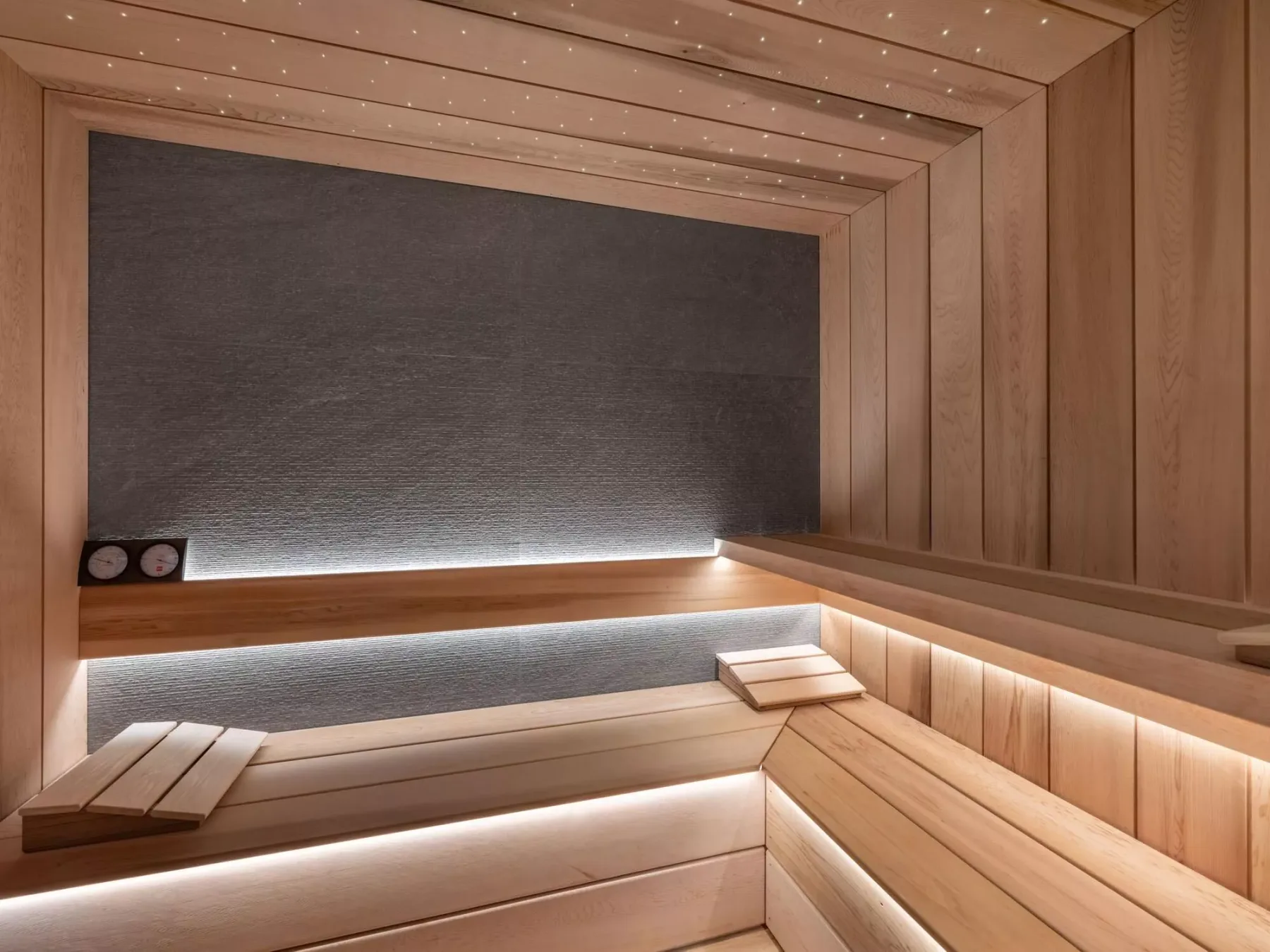 Una sauna revestida de madera, con bancos escalonados e iluminación tenue.