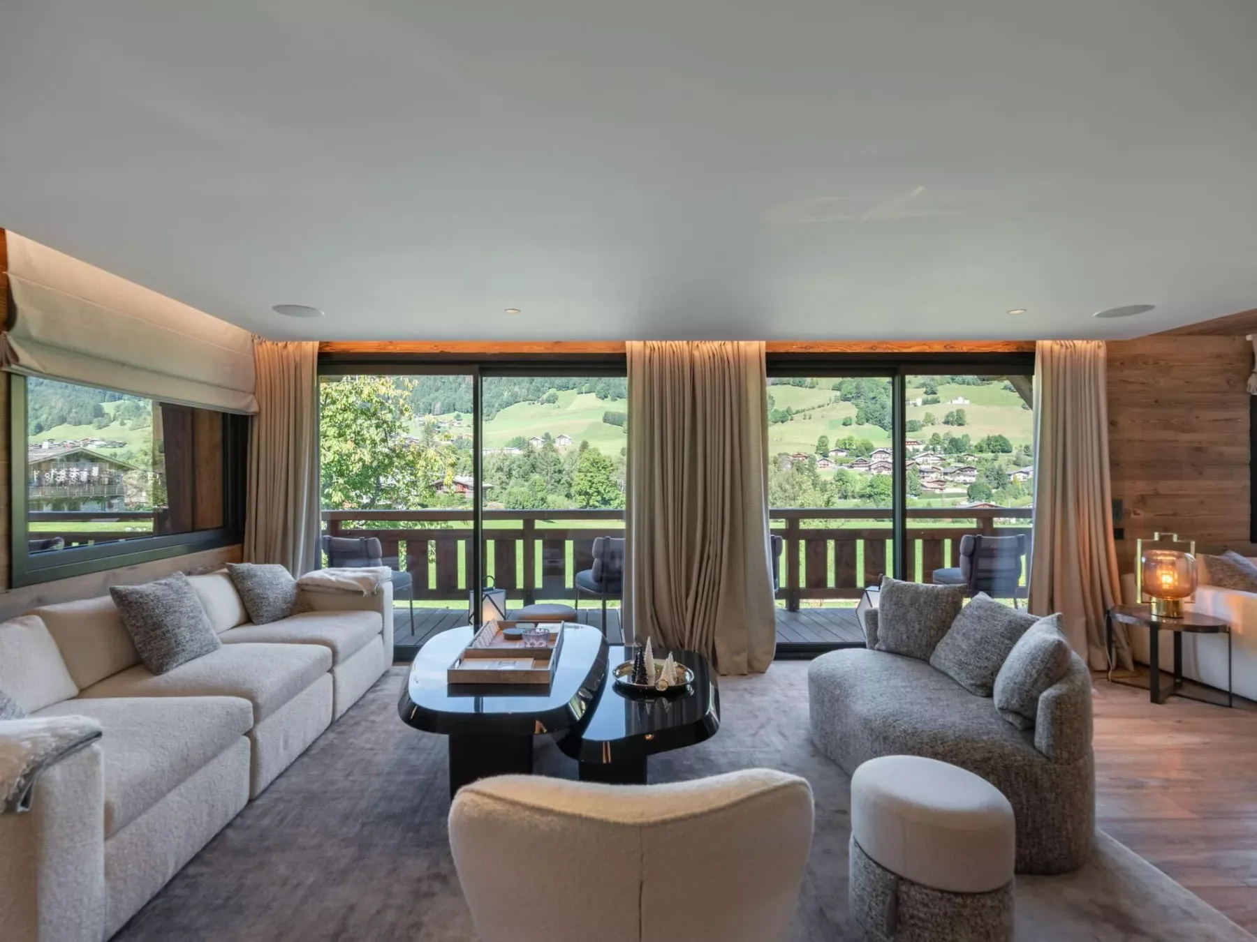 Una sala de estar con asientos junto a grandes ventanas con vistas a un paisaje verde.