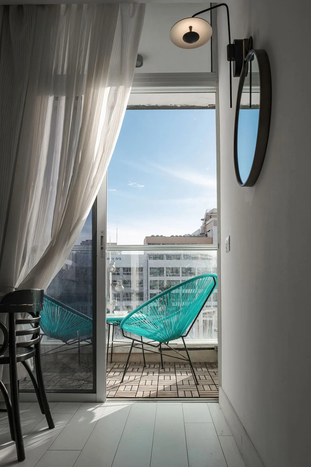 Room view toward a balcony with turquoise chairs
