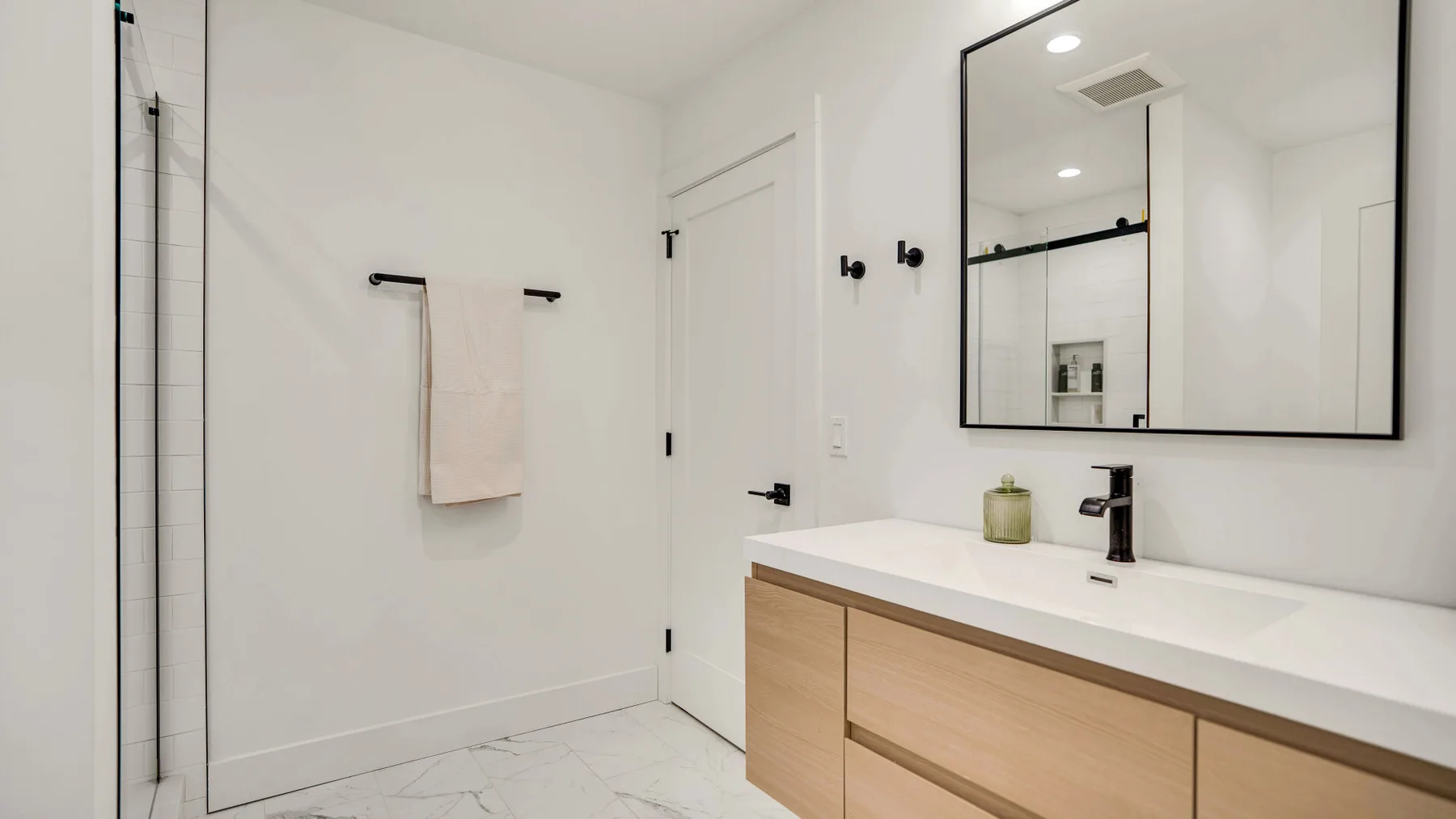 Un baño luminoso con lavabo, espejo de pared y ducha.