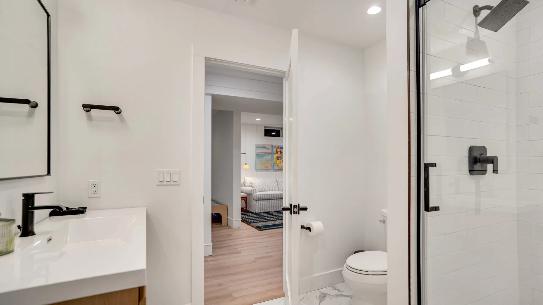 Un baño luminoso con lavabo, inodoro y ducha de vidrio.