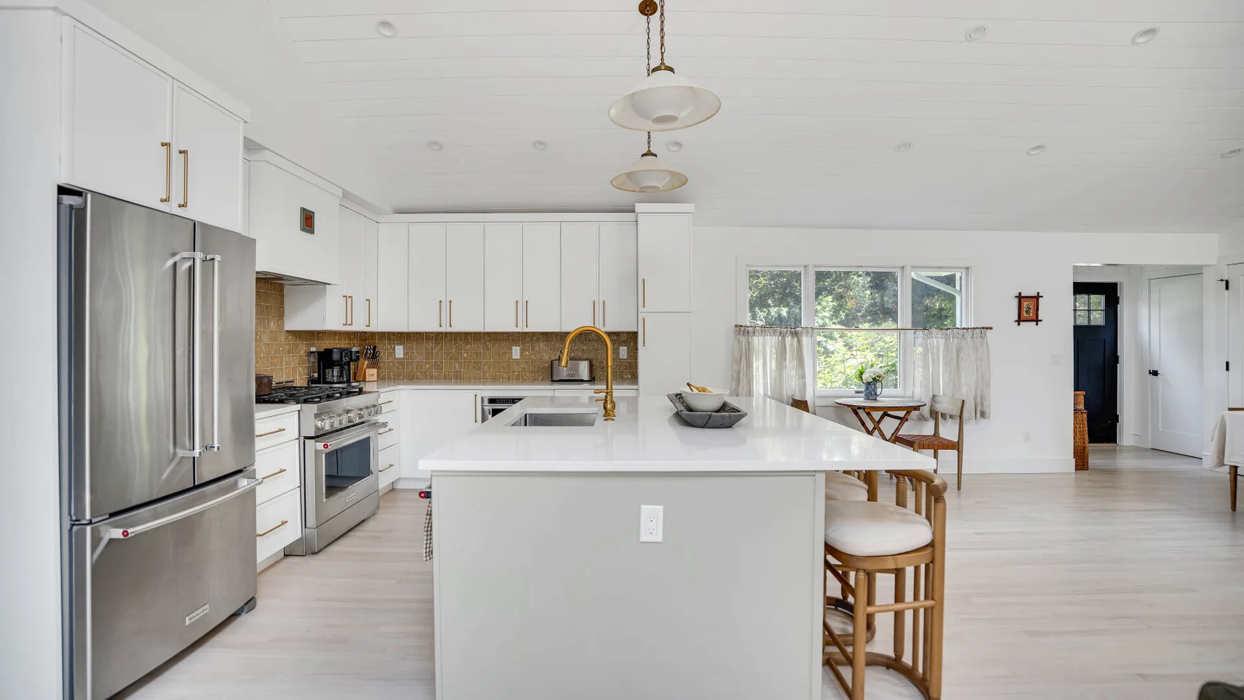 Una cocina luminosa con una isla grande y electrodomésticos de acero inoxidable.