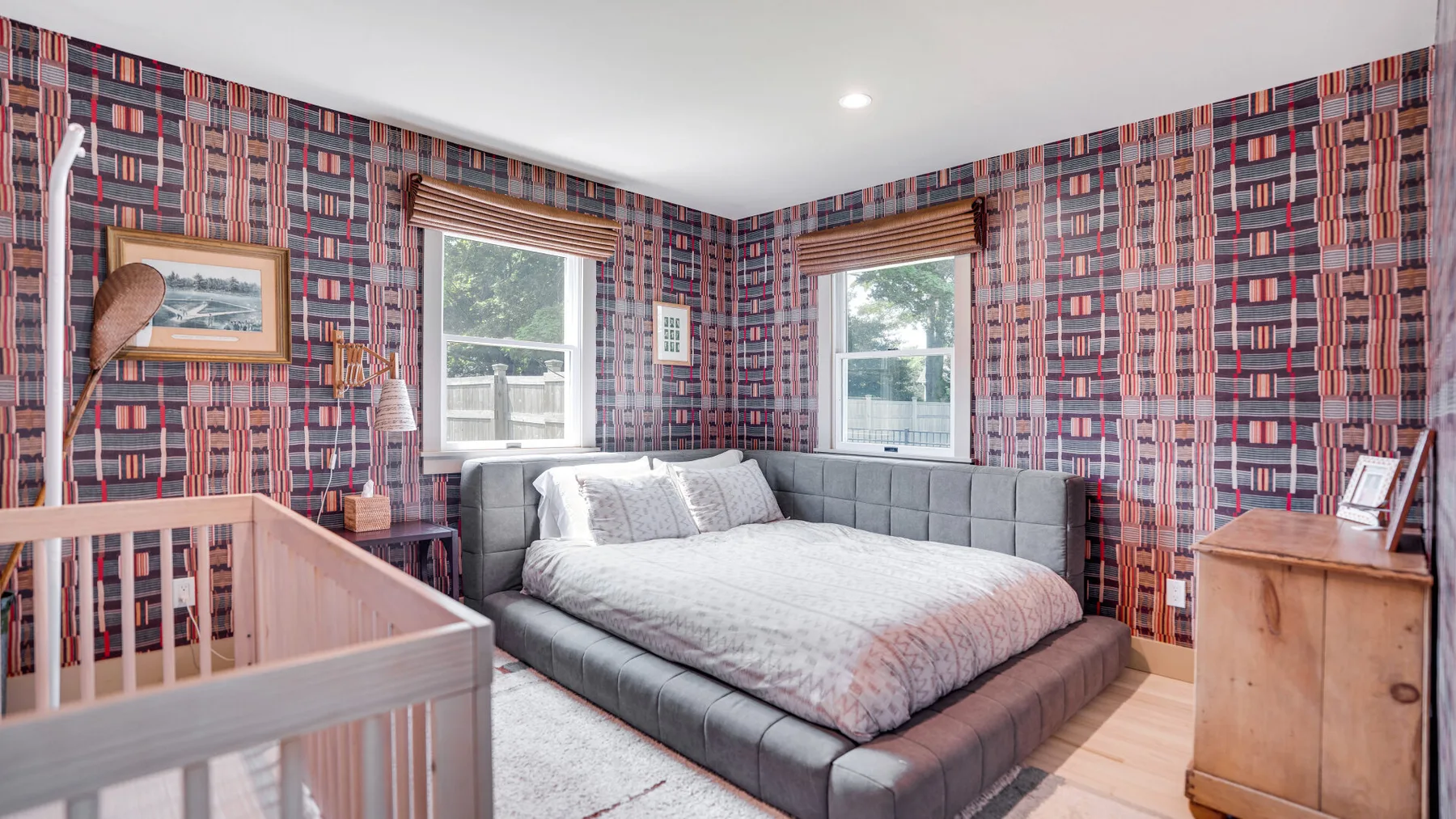 Un dormitorio con una cama grande, paredes estampadas y dos ventanas.