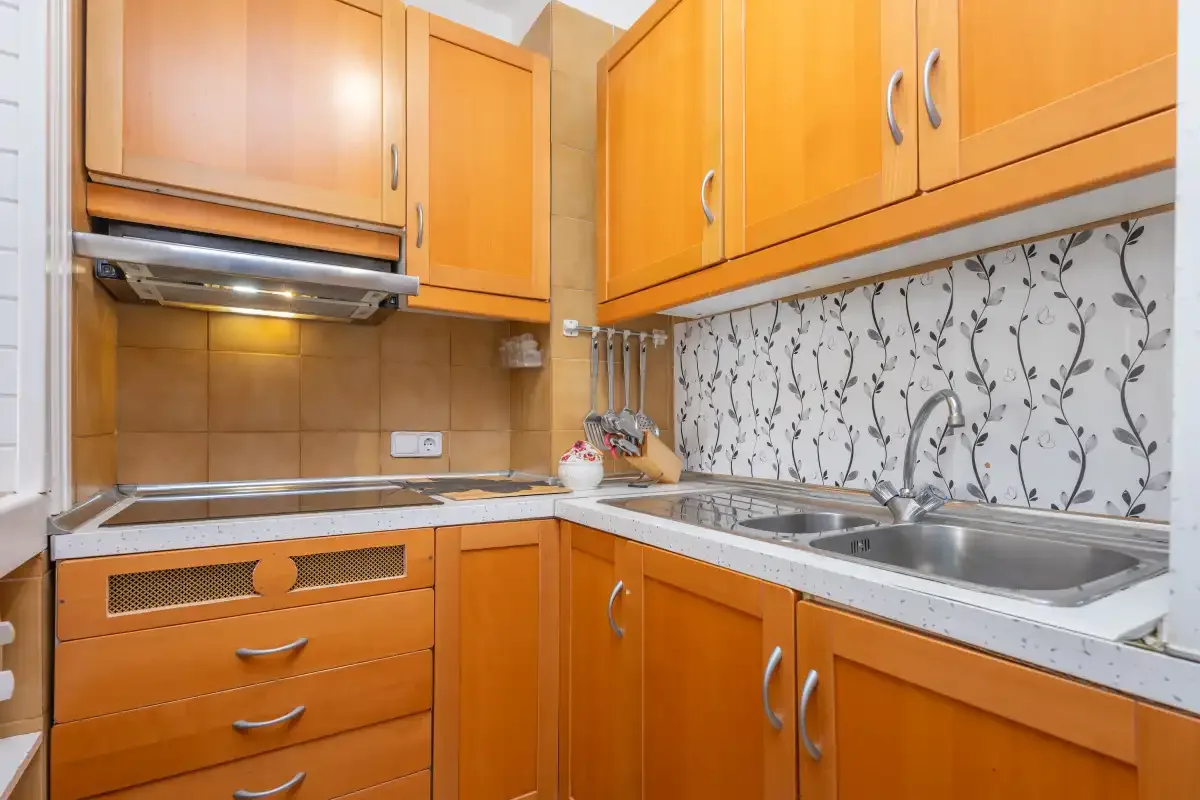 A fitted kitchen with orange cabinetry, a cooktop and a sink.