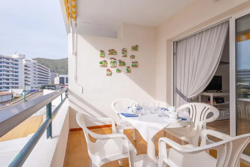 A balcony dining area with white seating and a table set with dishes.