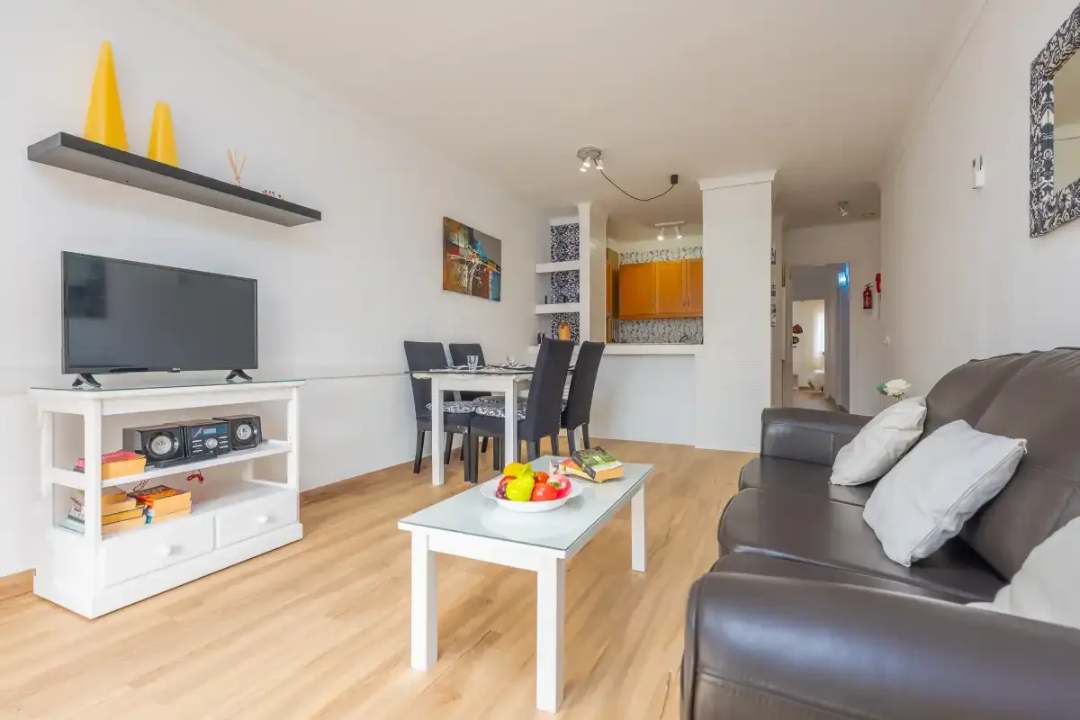 Living and dining area with a television, seating, and an open kitchen.
