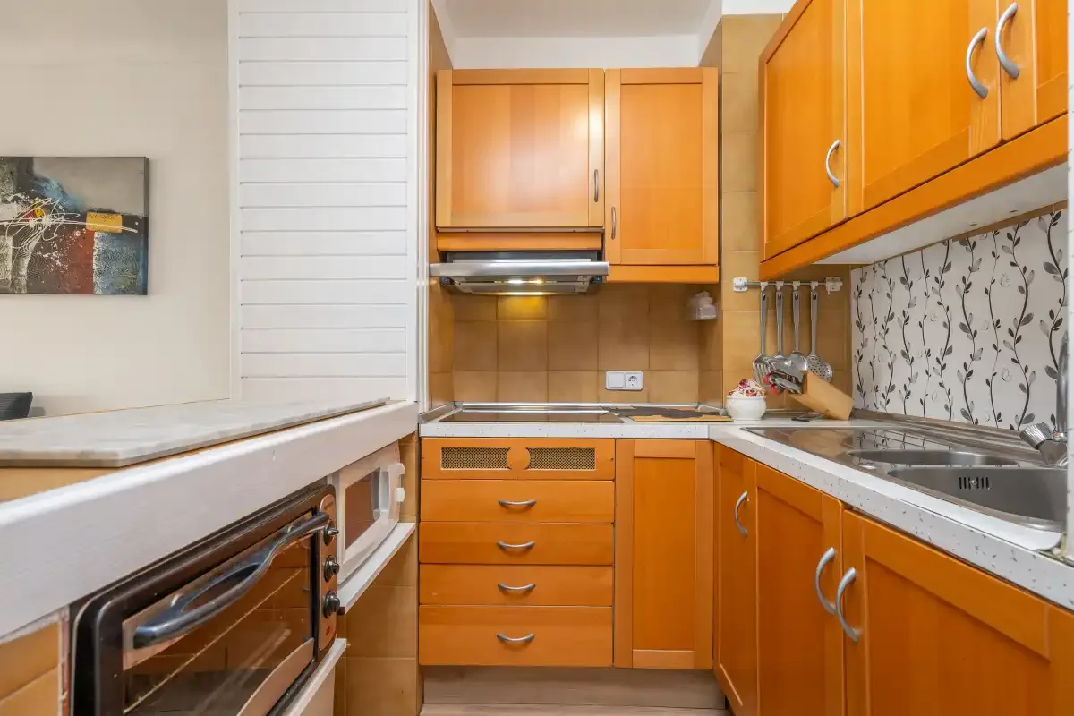 A compact kitchen with orange cabinets and a countertop oven.