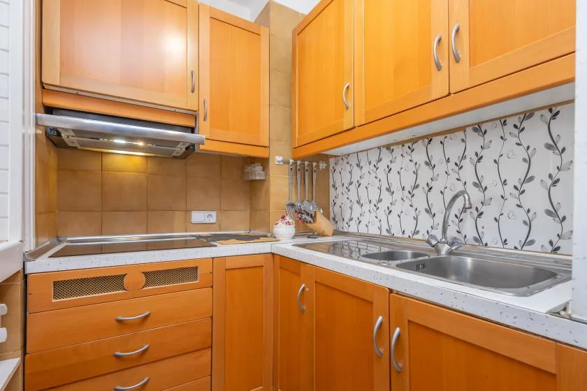 A kitchen with orange cabinets, a countertop, and a sink.