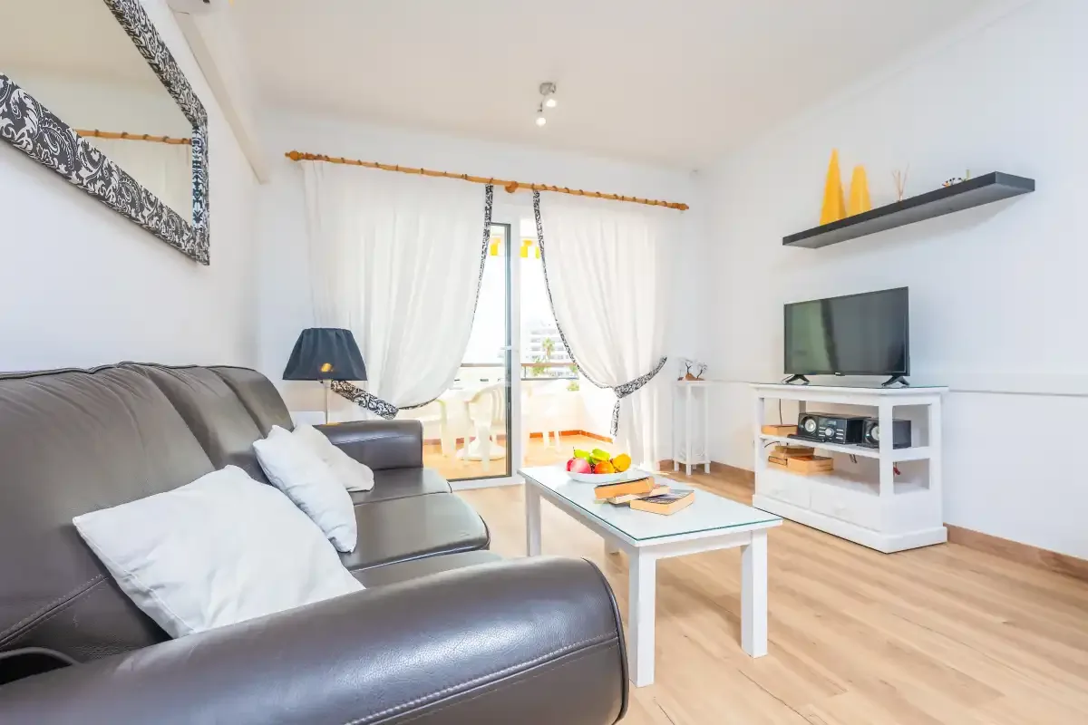A bright living room with seating, a coffee table, and a television.