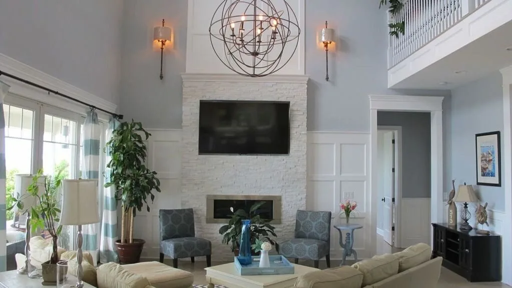Una sala luminosa con asientos alrededor de una chimenea de piedra y un televisor.