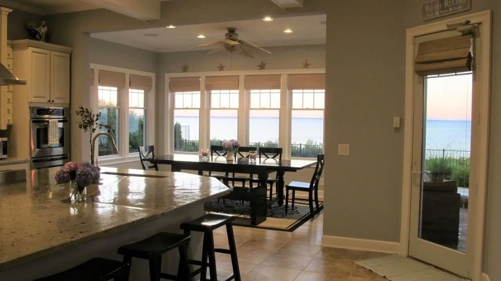 Una cocina luminosa y un comedor se abren a ventanas con vistas al agua.