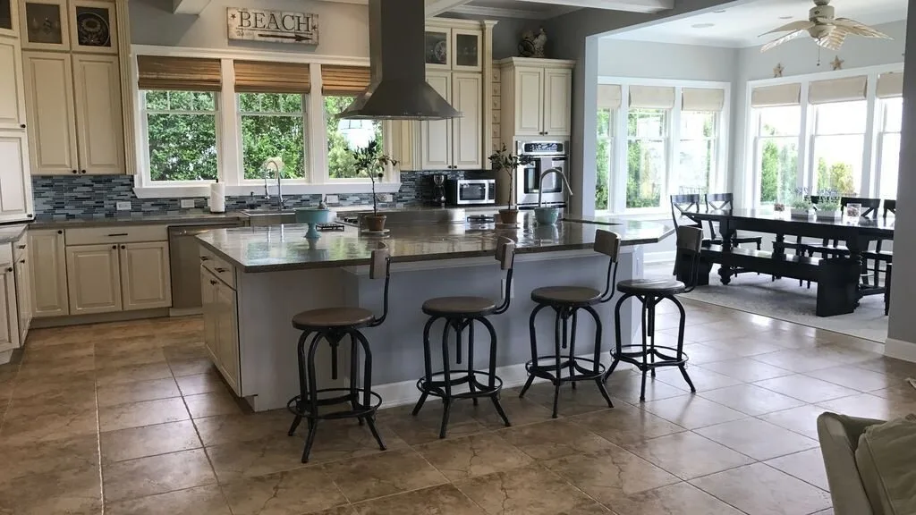 Una cocina luminosa con una isla y un comedor junto a grandes ventanas.