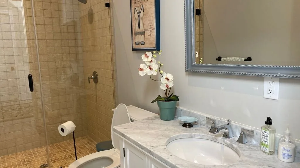 Un mueble de baño con lavabo está junto a una ducha de vidrio.
