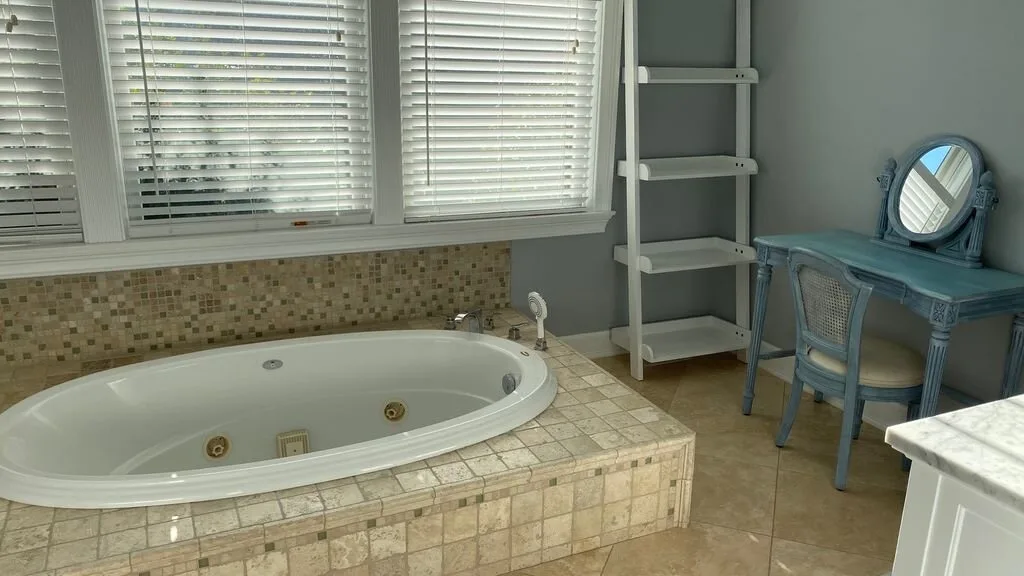 Un baño con una bañera empotrada bajo ventanas amplias.
