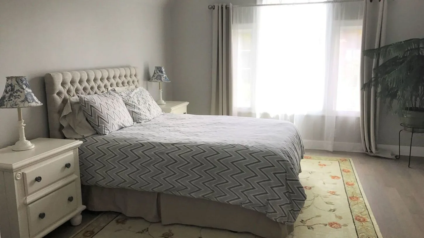 Un dormitorio con una cama grande, mesitas de noche y una ventana luminosa.