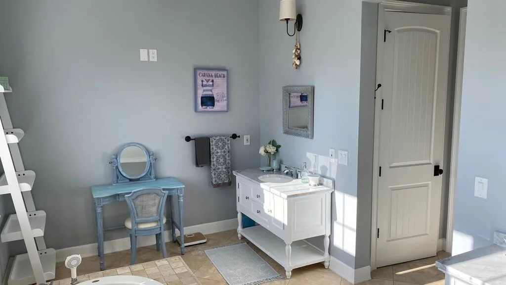 Un baño luminoso con tocador, espejo y una puerta abierta.