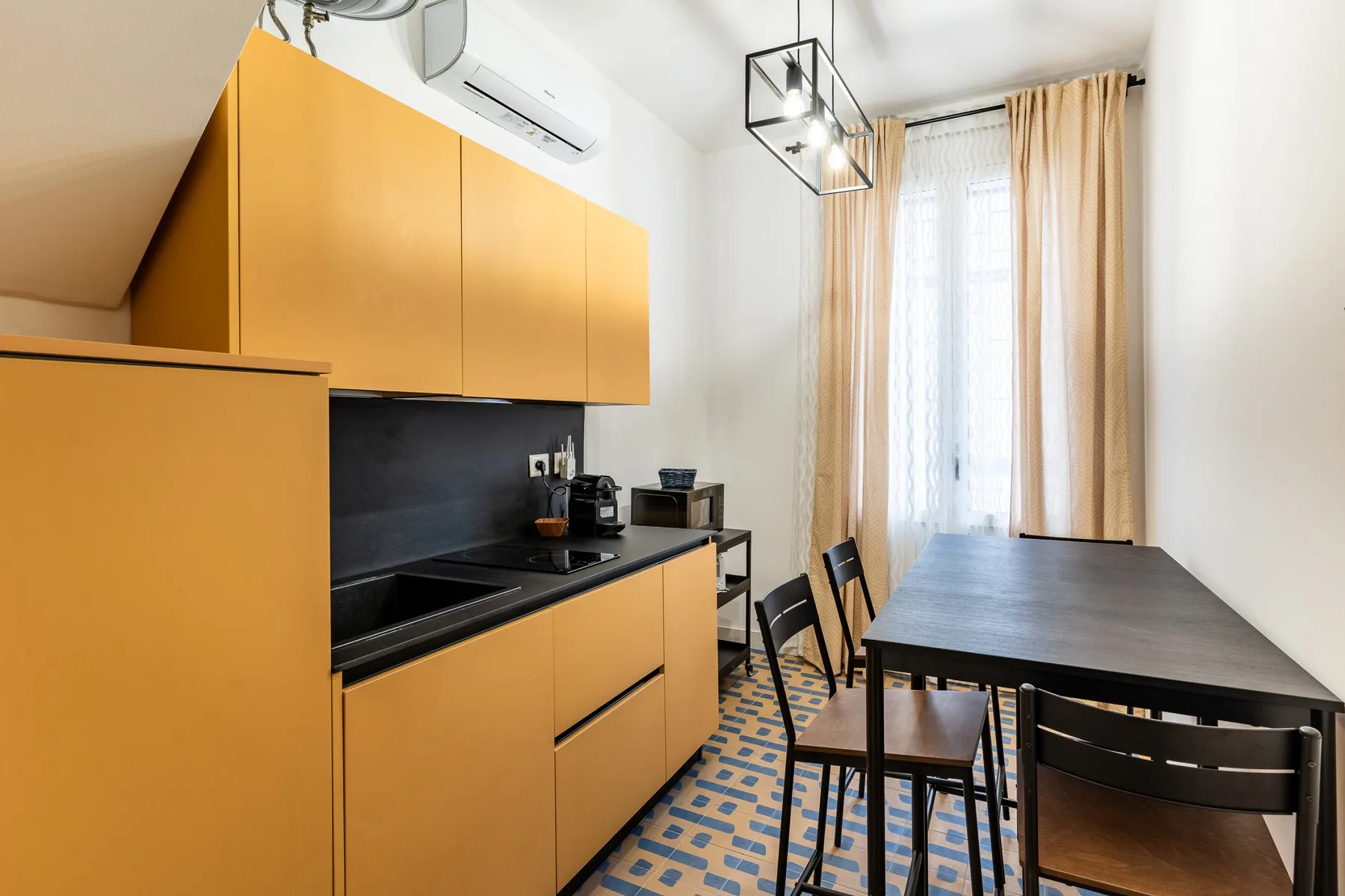 Un comedor con una mesa oscura junto a gabinetes de cocina color mostaza.