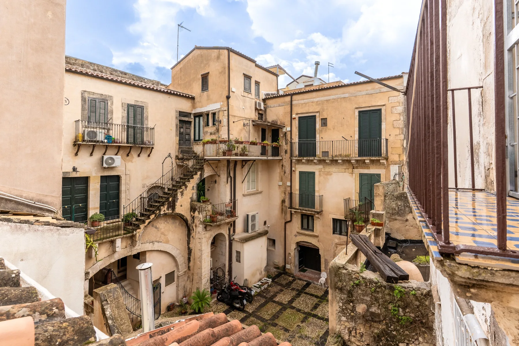 Un patio histórico rodeado de edificios contiguos, balcones y escaleras exteriores.