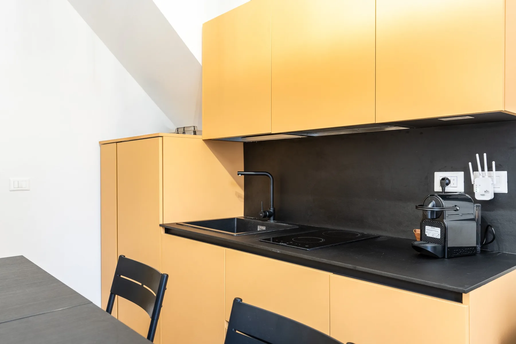 Una cocina moderna con gabinetes naranjas, una encimera oscura y un fregadero.