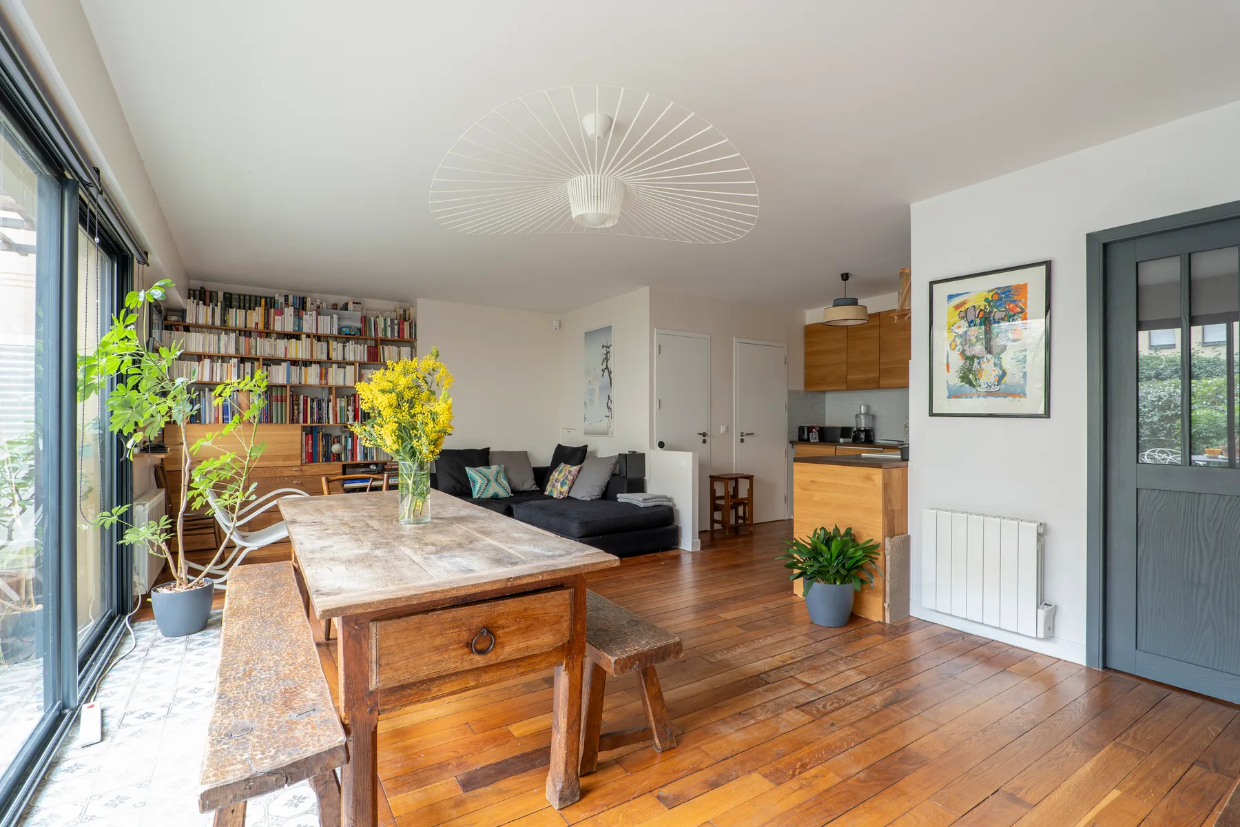 Living room with an open kitchen, dining table, and bookshelf.