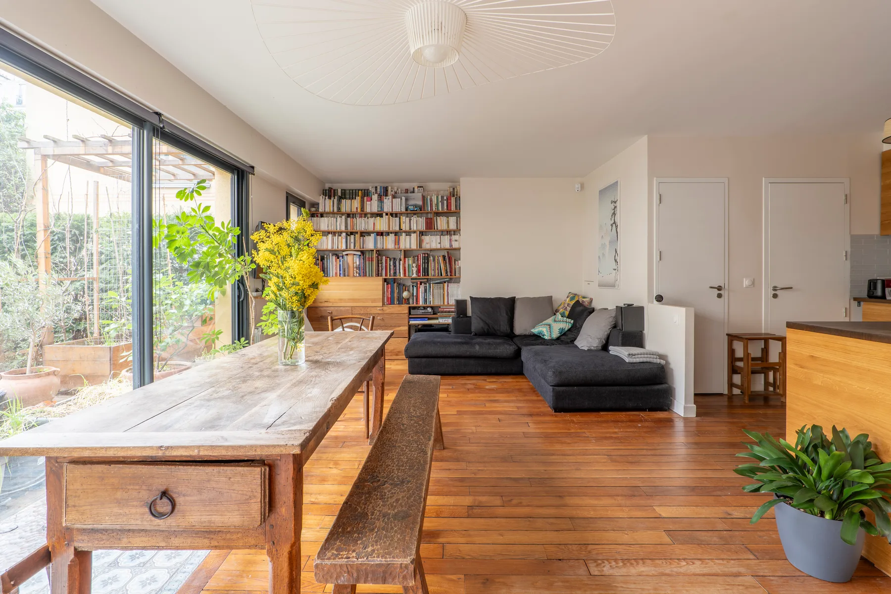 A living room with a sectional seating area, bookshelves, and large windows.