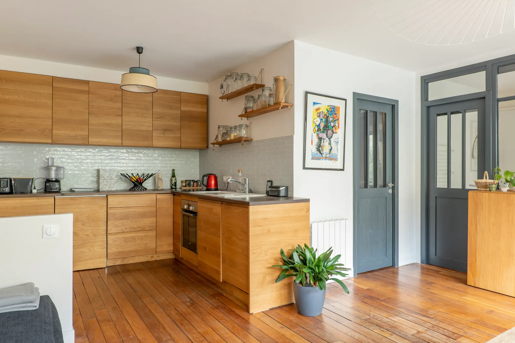 A kitchen with wood cabinets, a counter, and a potted plant.