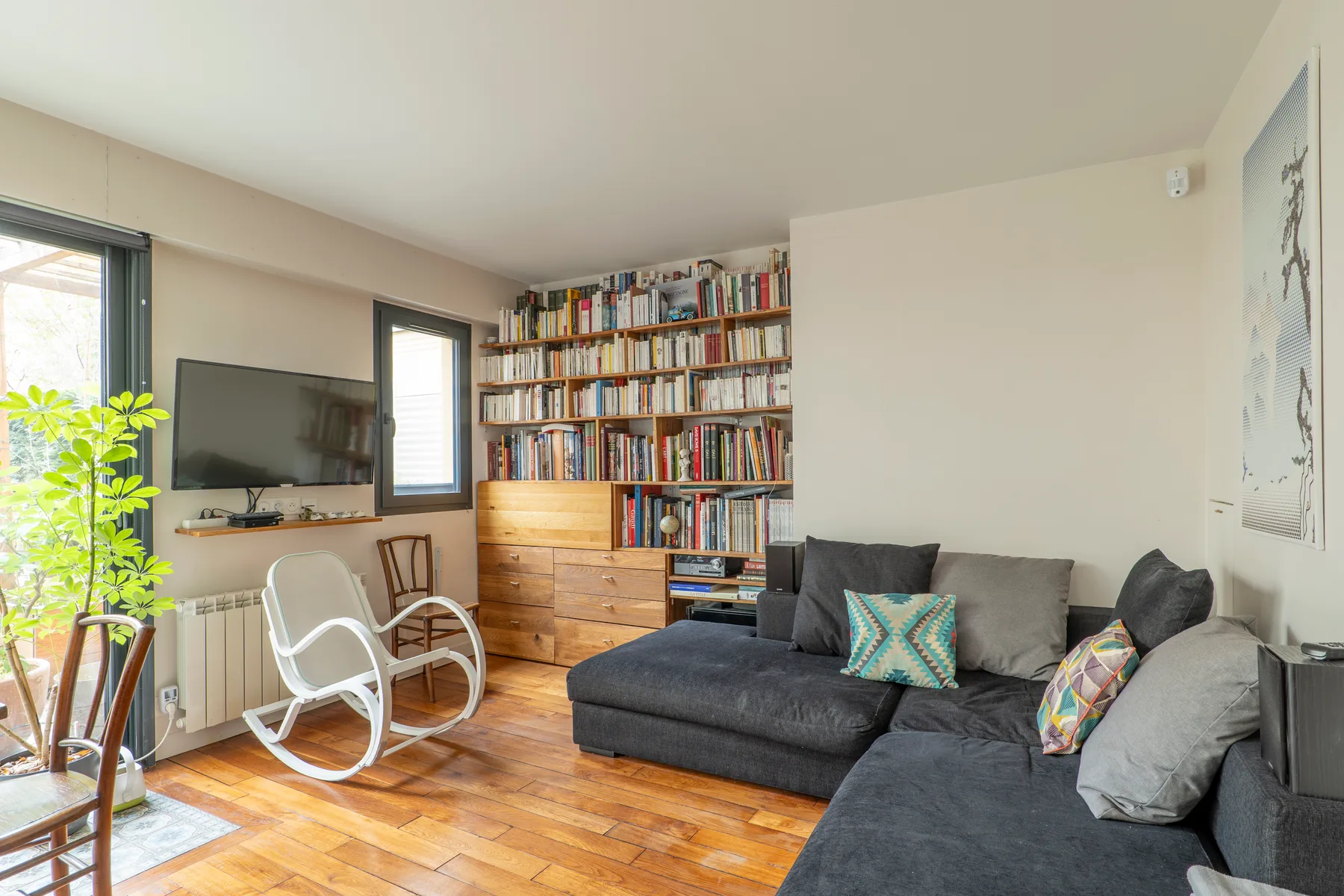 A living room with a sectional sofa, television, and wall of bookshelves.