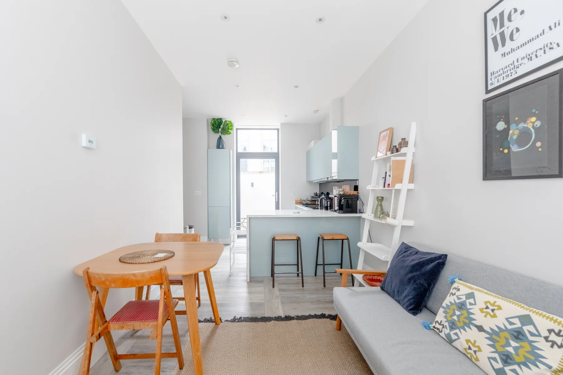 A bright living and dining area with a compact kitchen and gray seating.