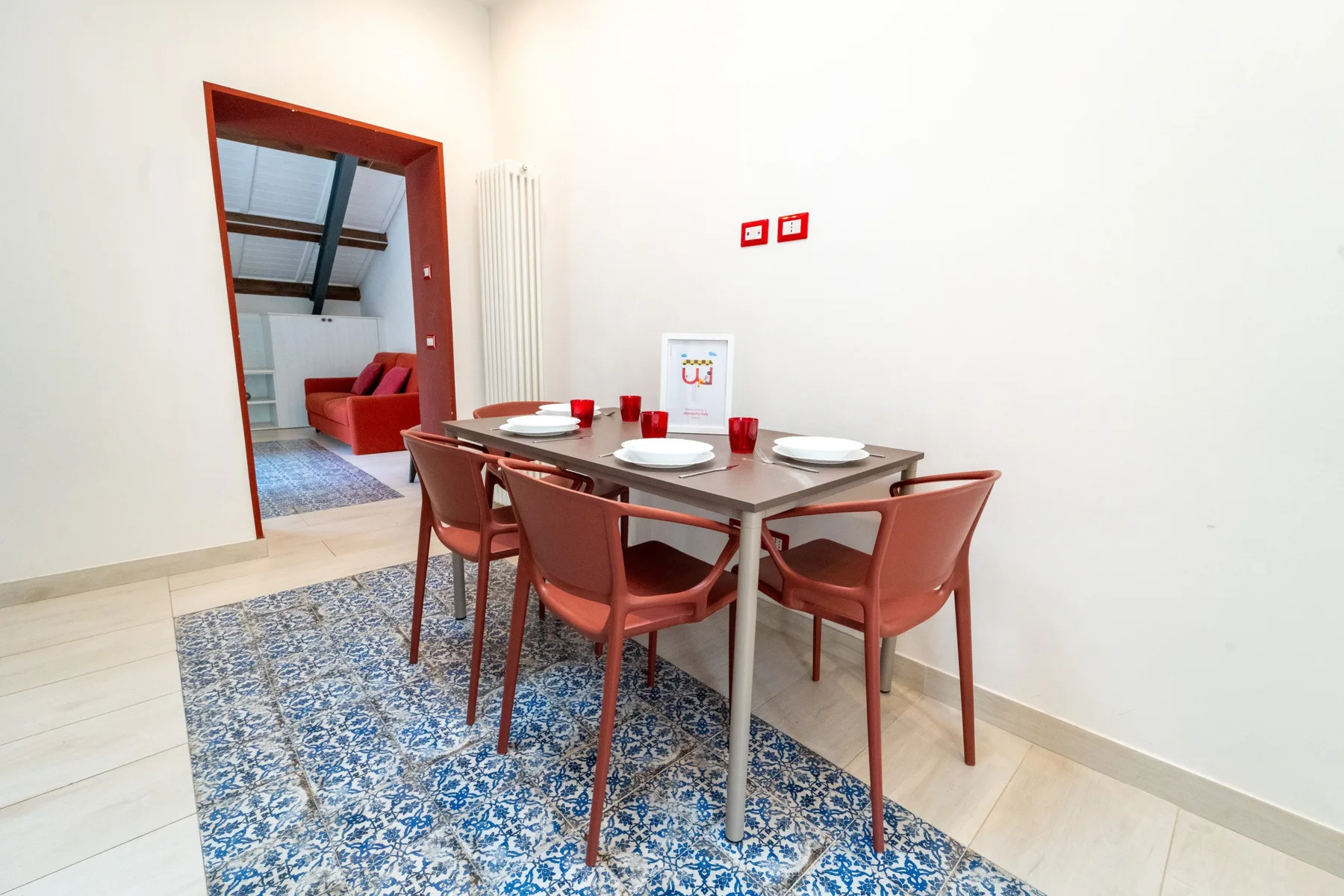 A dining area with a table and reddish seating on a patterned rug.