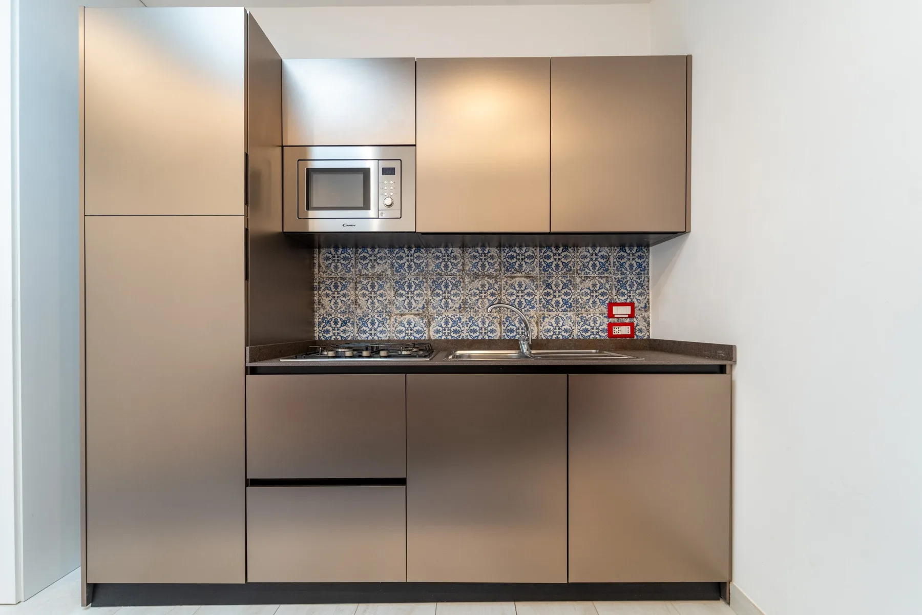 A modern kitchen with built-in cabinets, a microwave, and patterned backsplash.