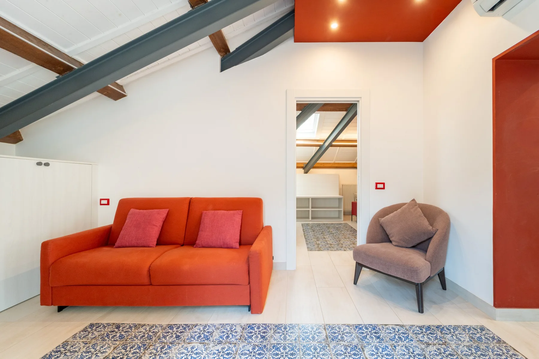 A bright living room with orange seating and a small patterned rug.