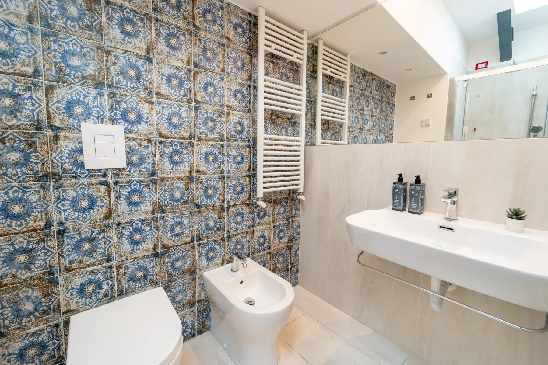 A bathroom with a wide sink and blue patterned wall tiles.