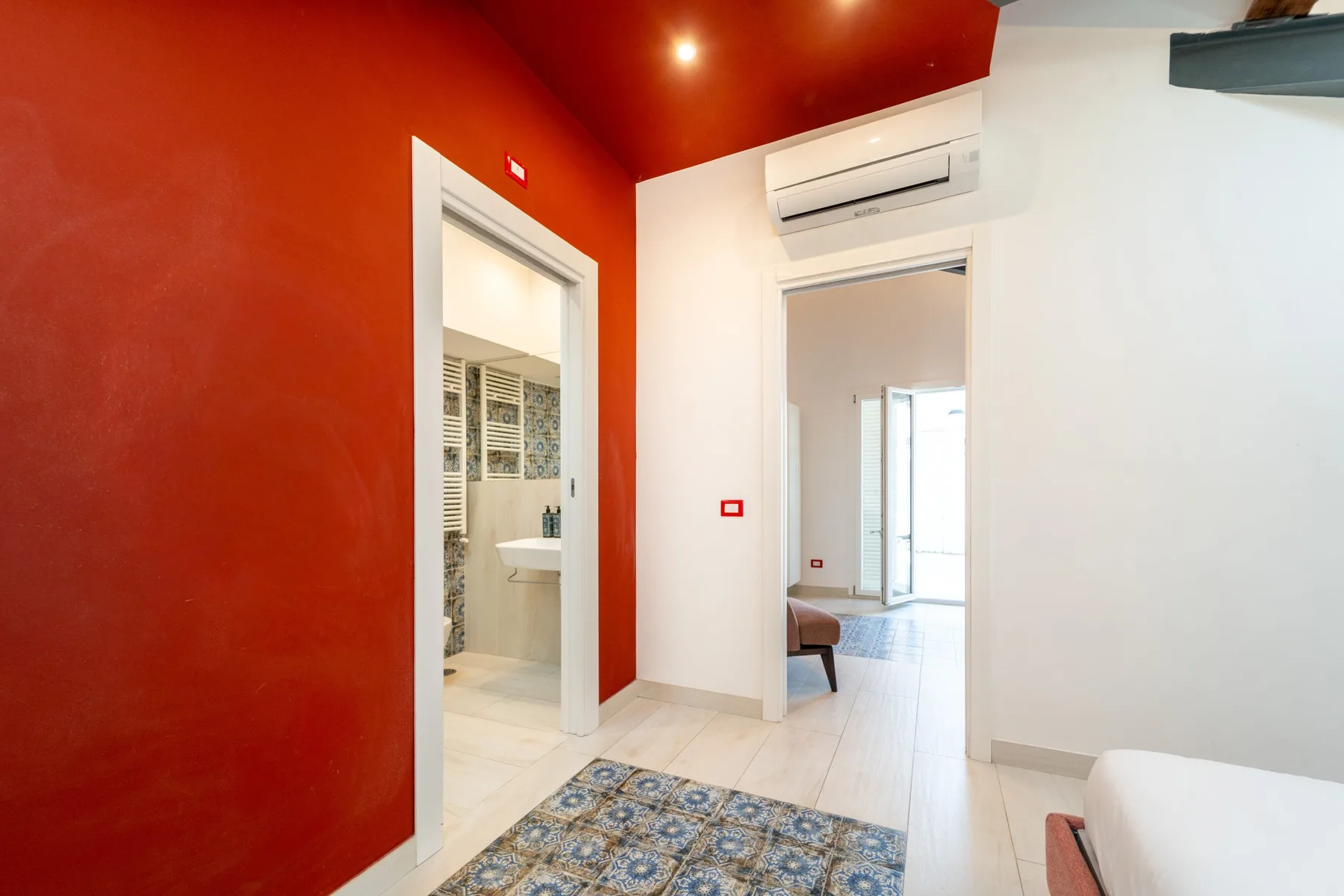A bright interior hallway with red walls and open doorways.