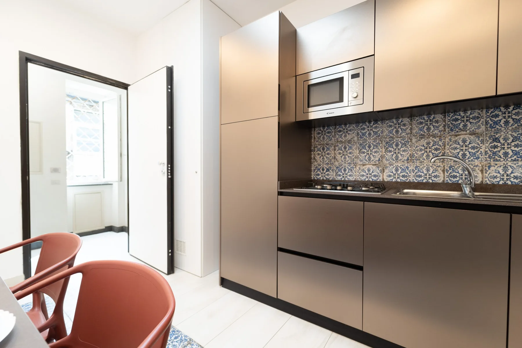 A modern kitchen with dark cabinetry, a built-in microwave, and patterned backsplash.