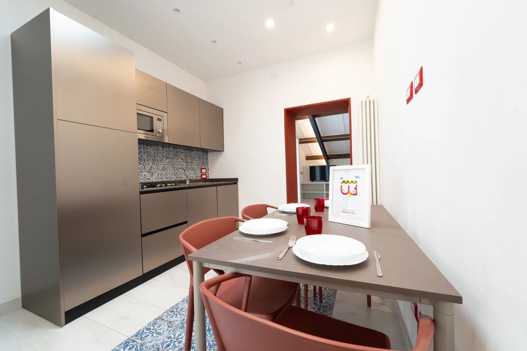 A dining area with a table set with dishes beside a compact kitchen.