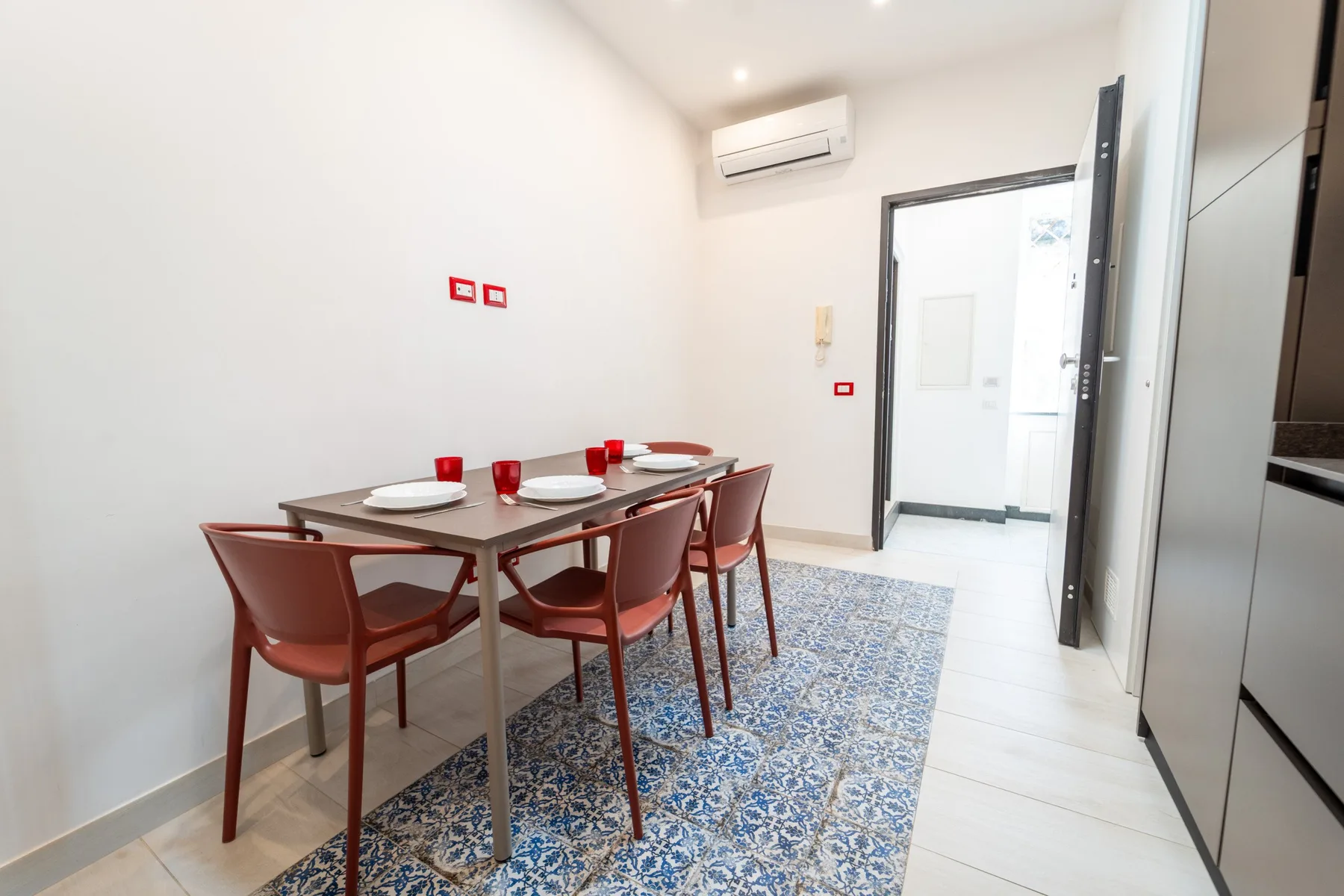 A dining area with a table and chairs beside a patterned rug.