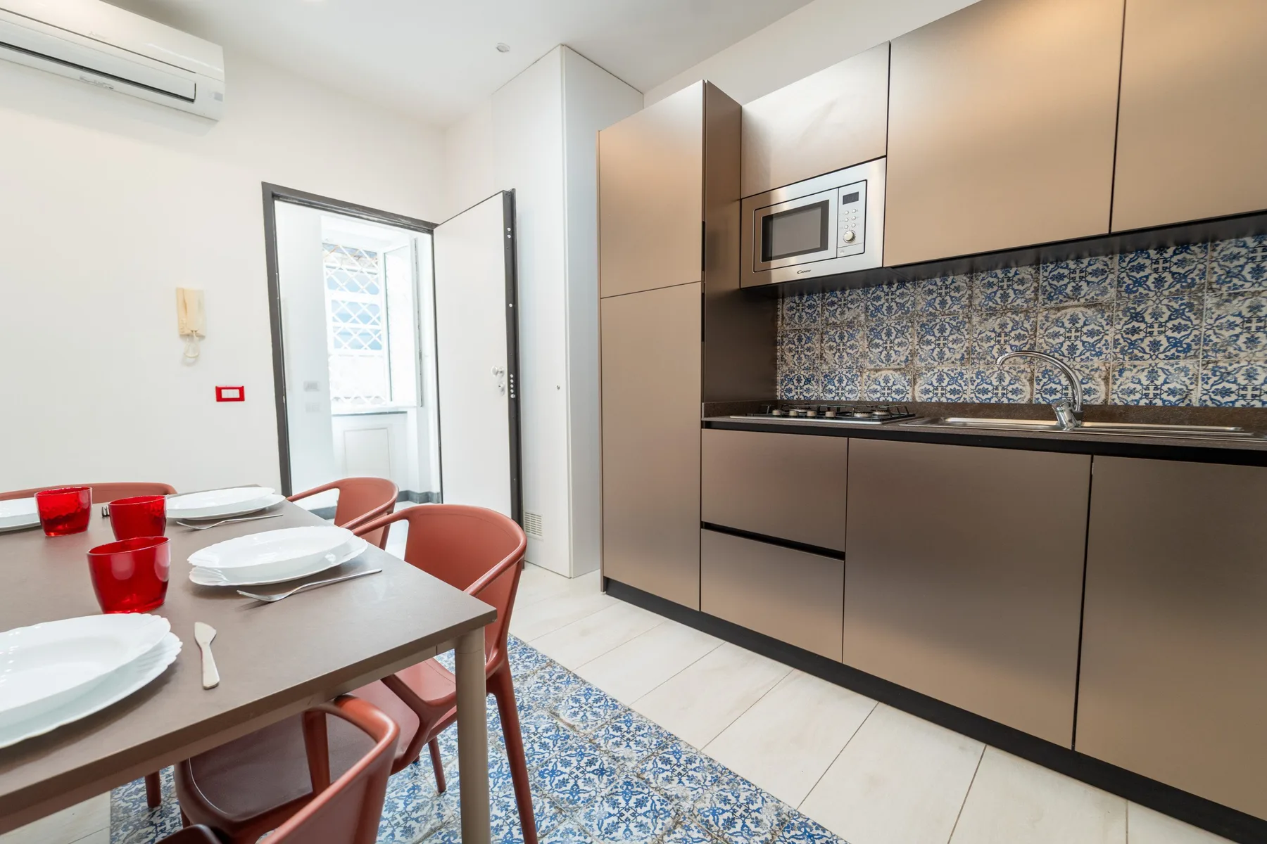 A modern kitchen with a dining table and patterned tile backsplash.