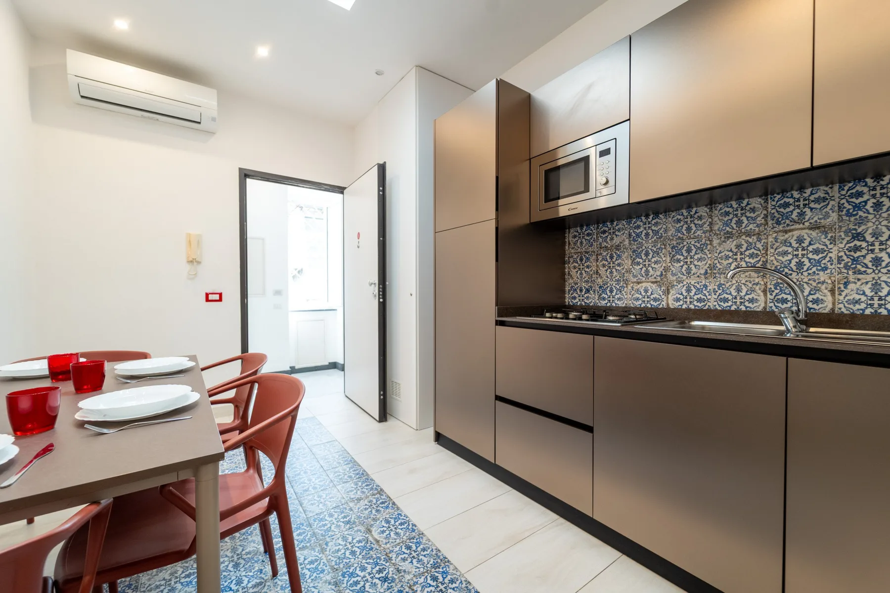 A modern kitchen with a dining table and patterned tile backsplash.