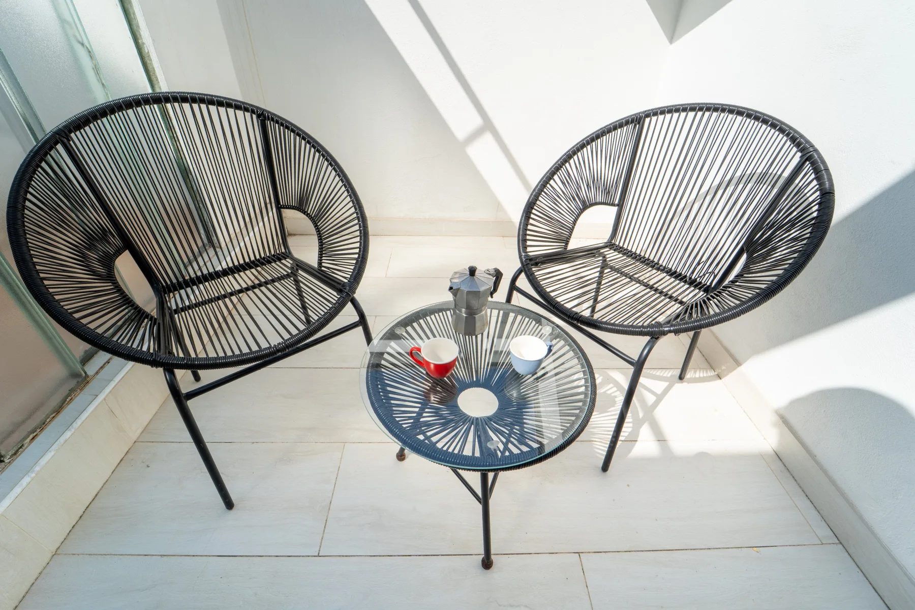 A small seating area with two woven chairs around a glass-topped table.