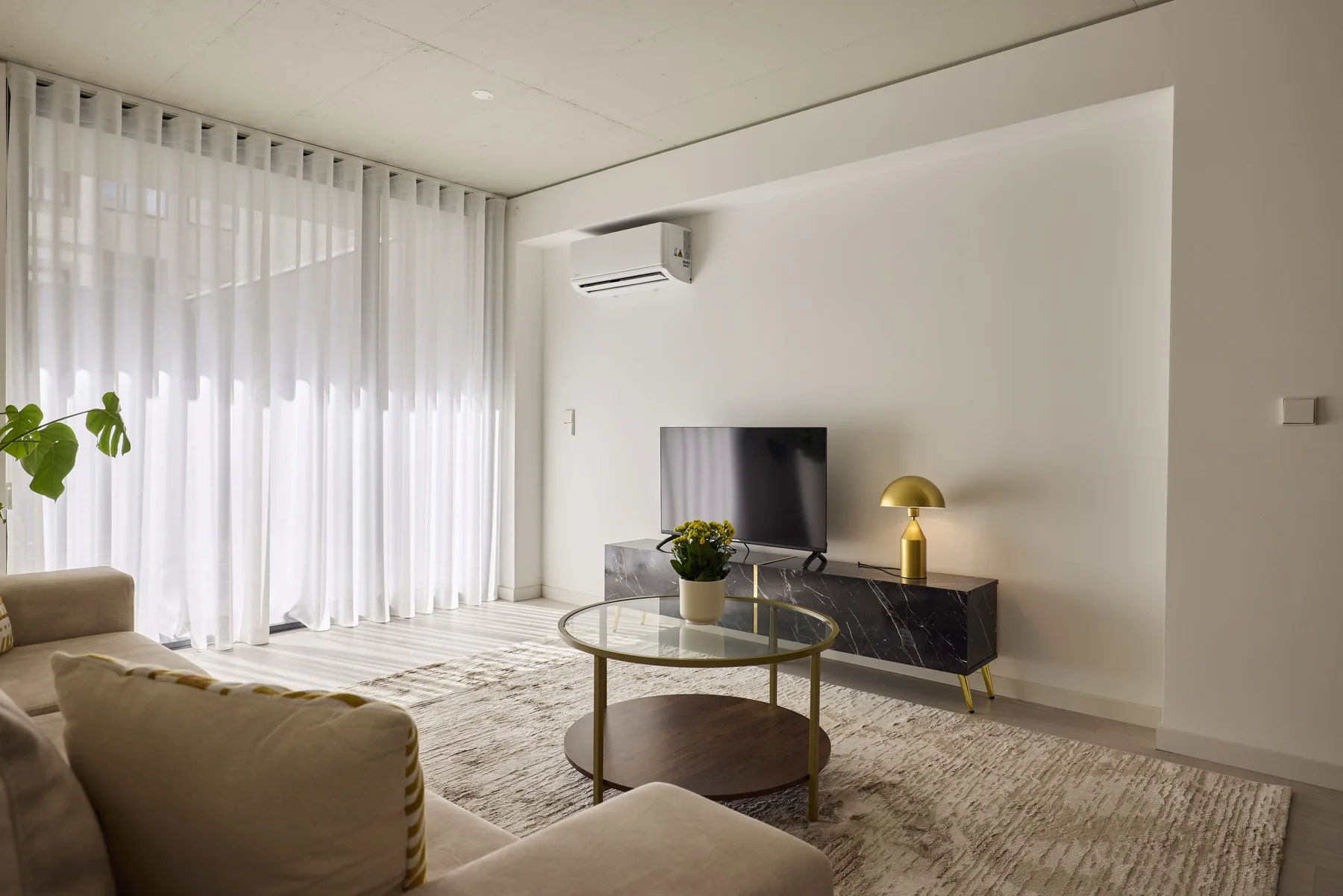 Una sala luminosa con asientos, una mesa redonda de cristal y un televisor.