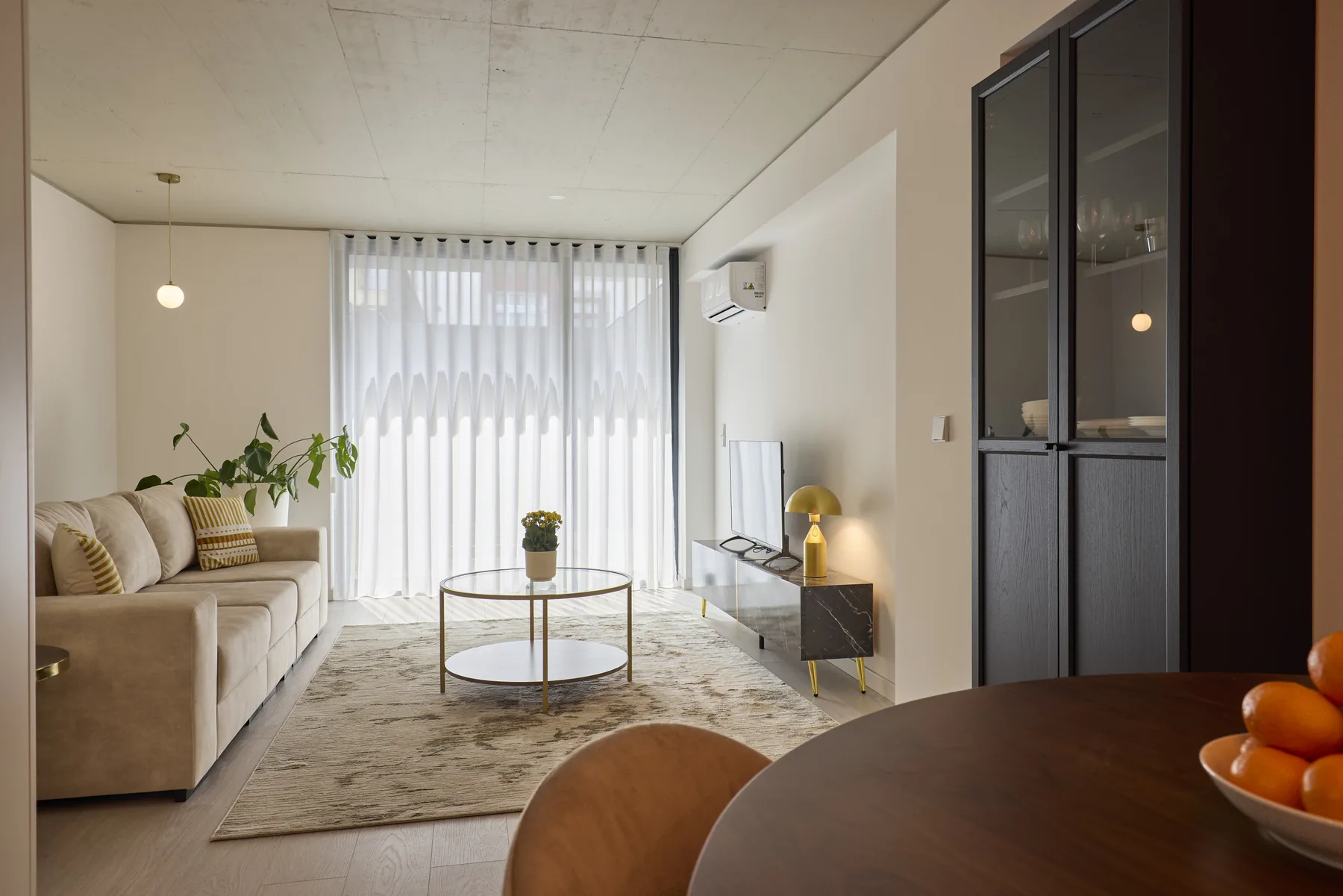 Una sala luminosa con asientos, una mesa de centro redonda y cortinas translúcidas.