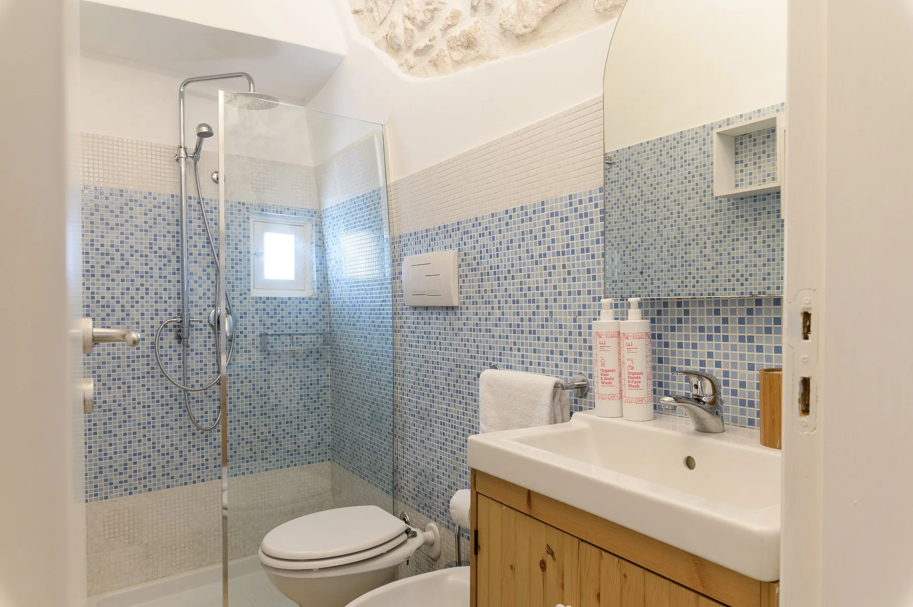 Un baño con azulejos, ducha de vidrio, inodoro y lavabo.