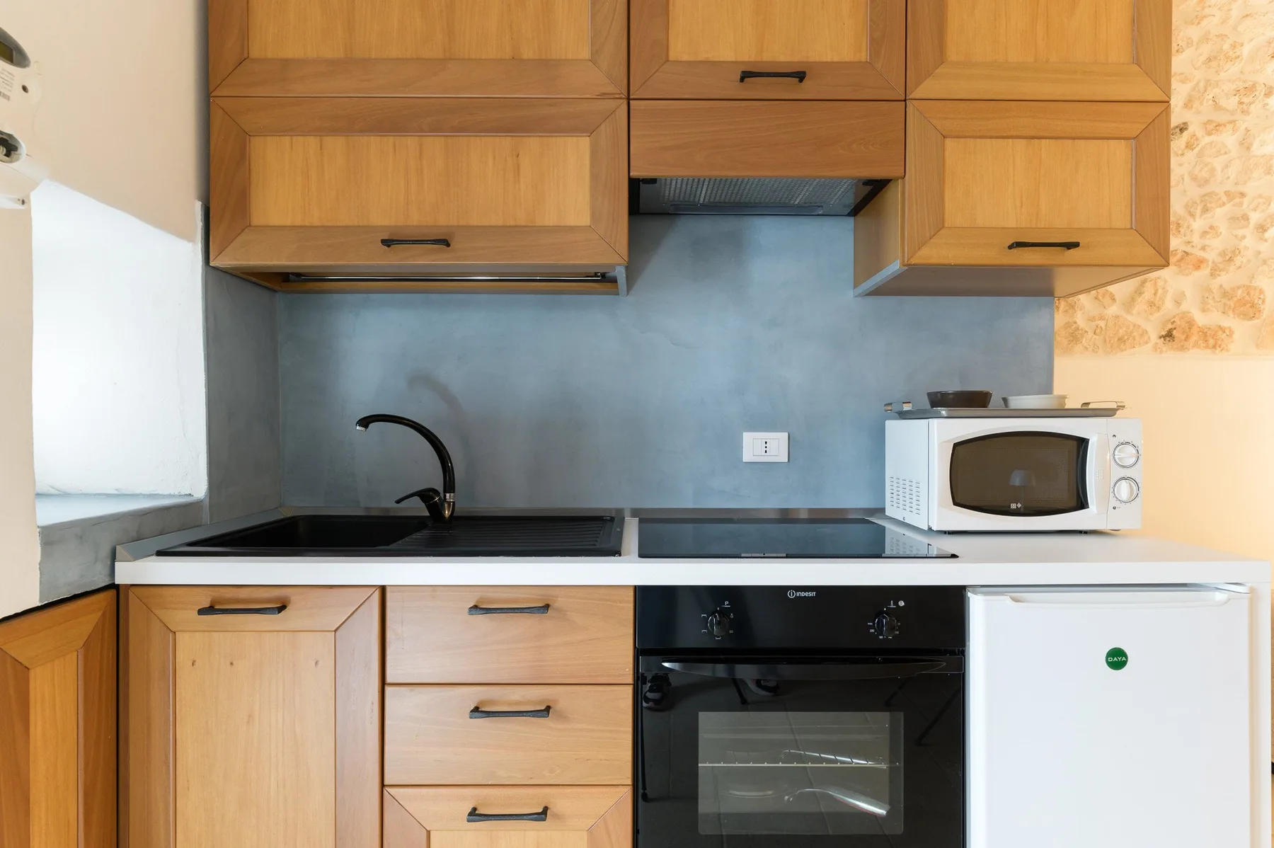 Una cocina compacta con gabinetes de madera, una encimera y electrodomésticos integrados.