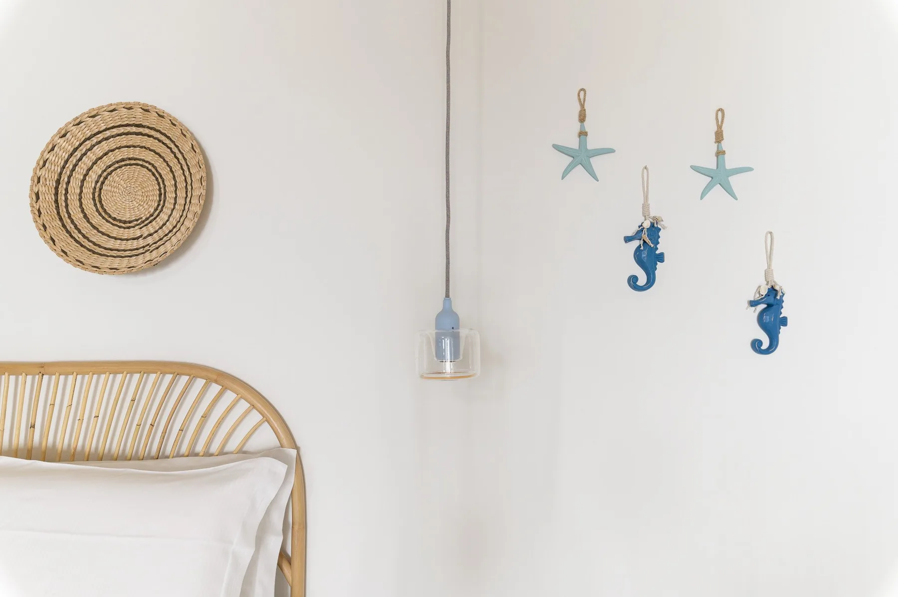 A bedroom corner with a woven wall decoration and hanging sea-themed ornaments.