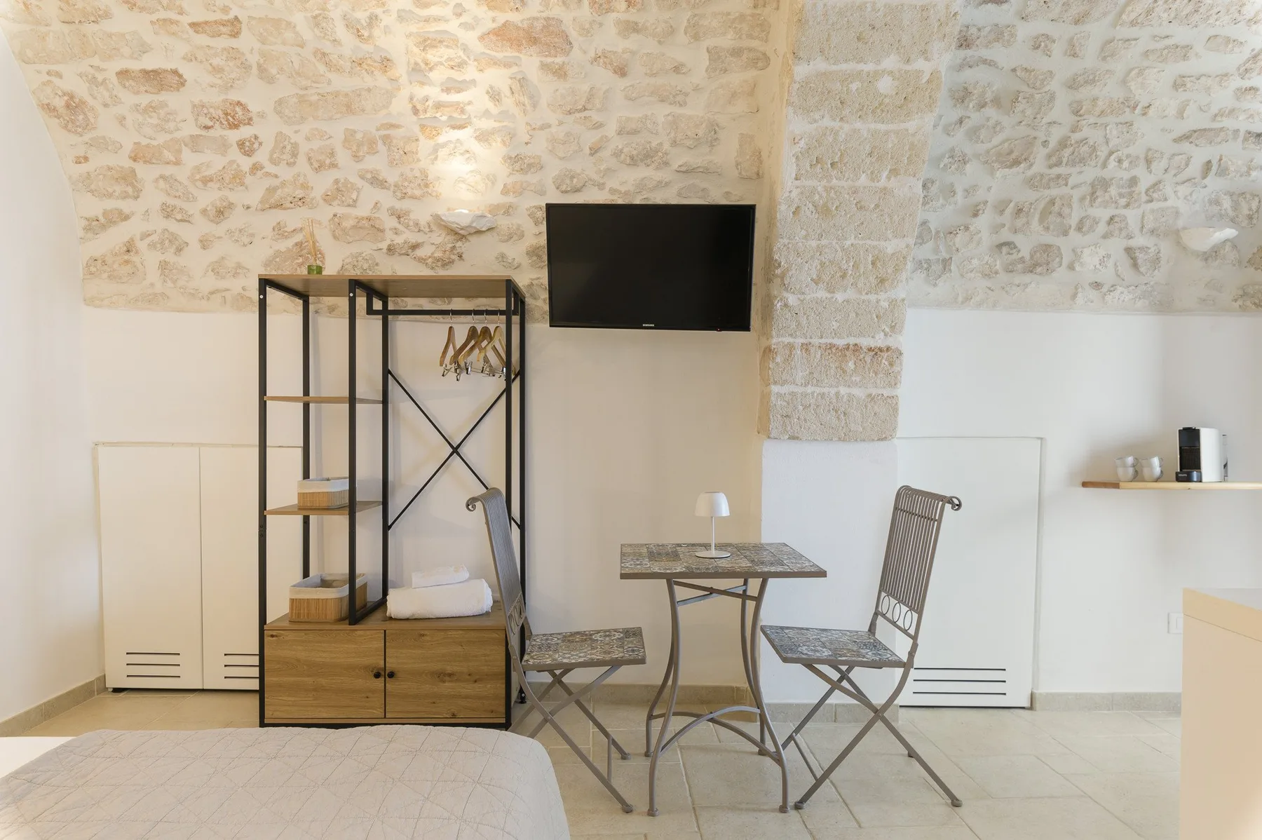 Un dormitorio luminoso con una mesa pequeña y asientos bajo paredes de piedra expuesta.