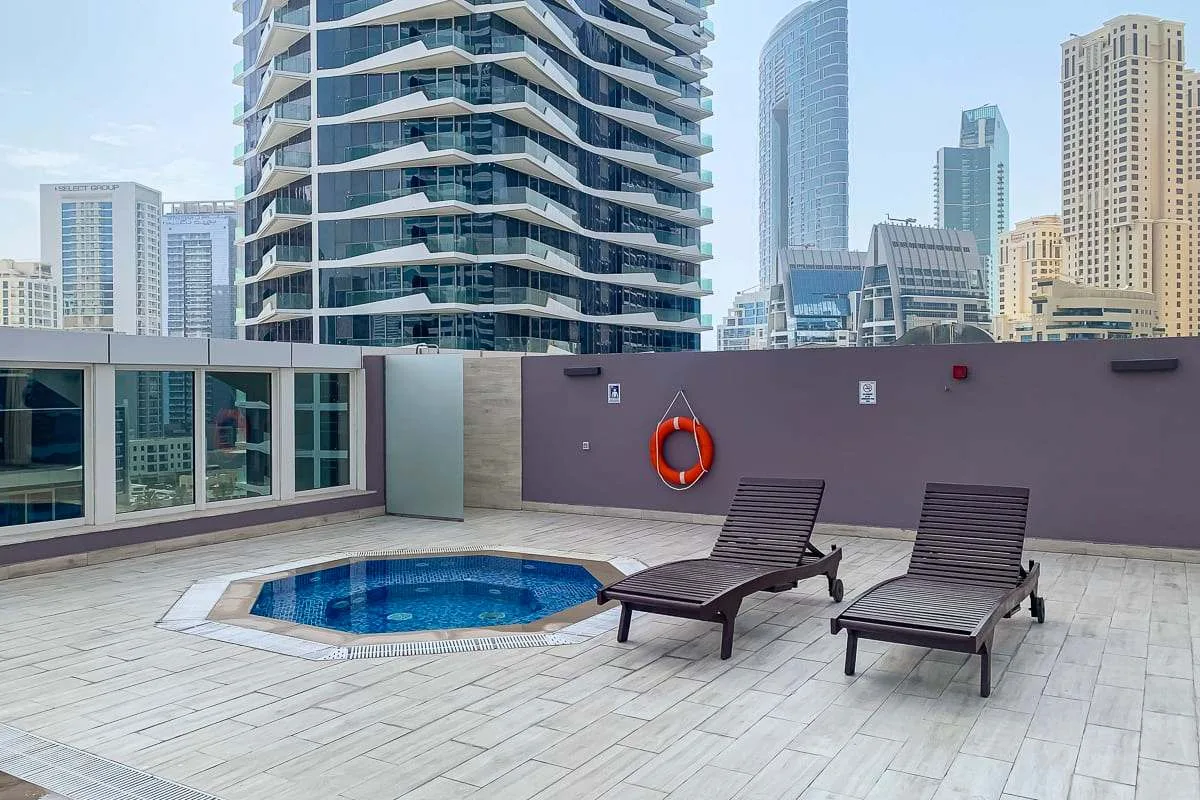 Una terraza en la azotea tiene una piscina pequeña y dos tumbonas, con edificios de la ciudad a la vista.