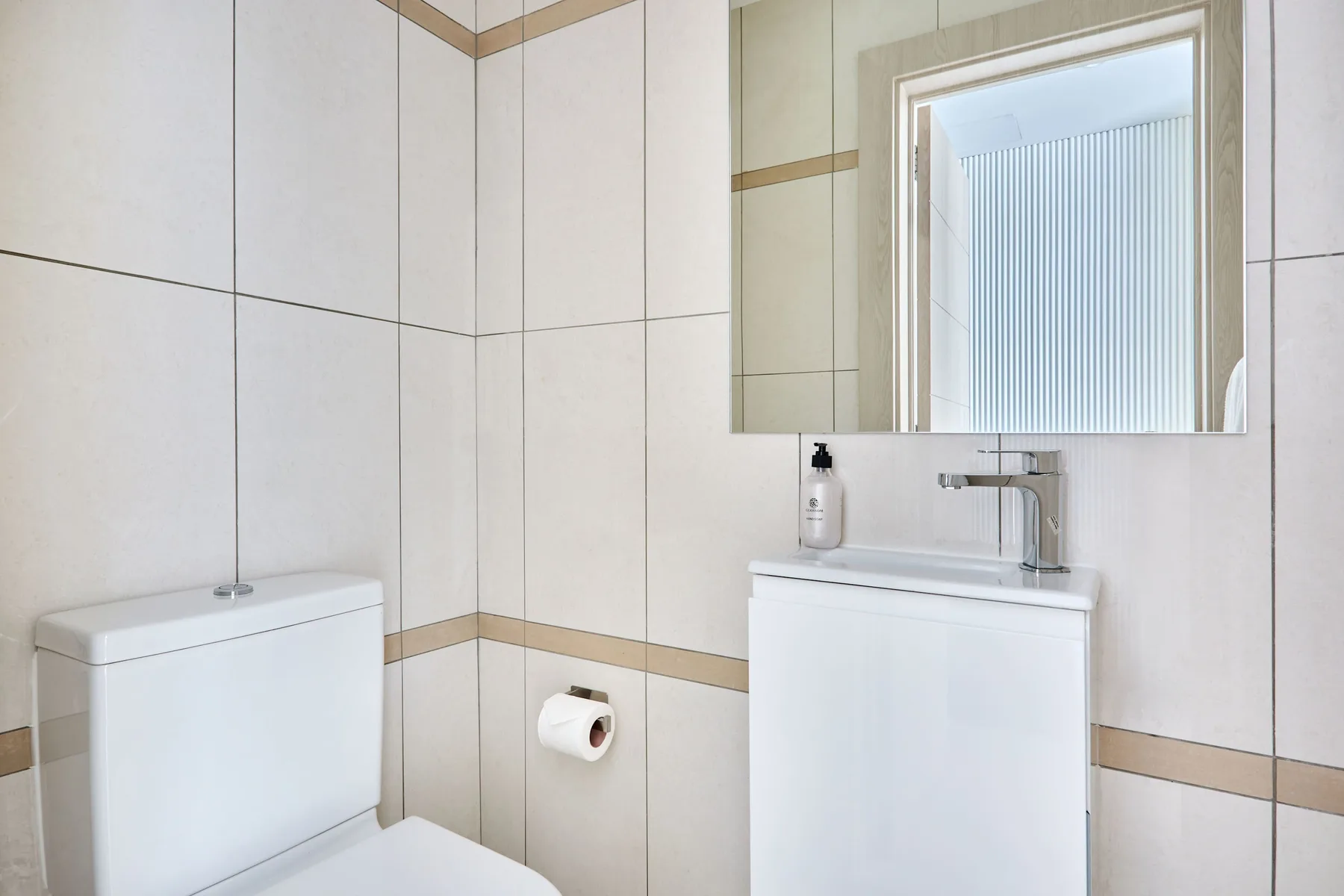 Un baño con azulejos, inodoro, lavabo y espejo.
