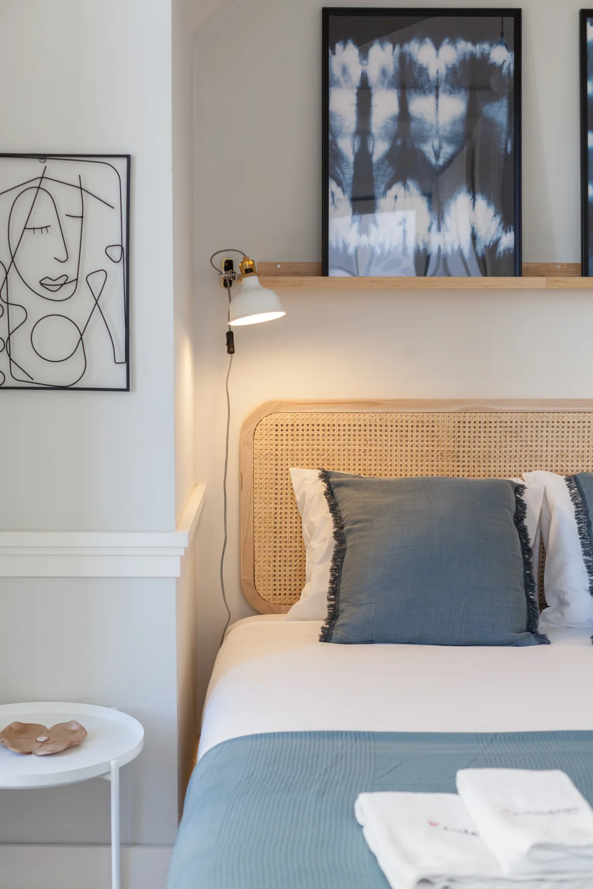 Un dormitorio con una cama bien tendida y obras enmarcadas en la pared.